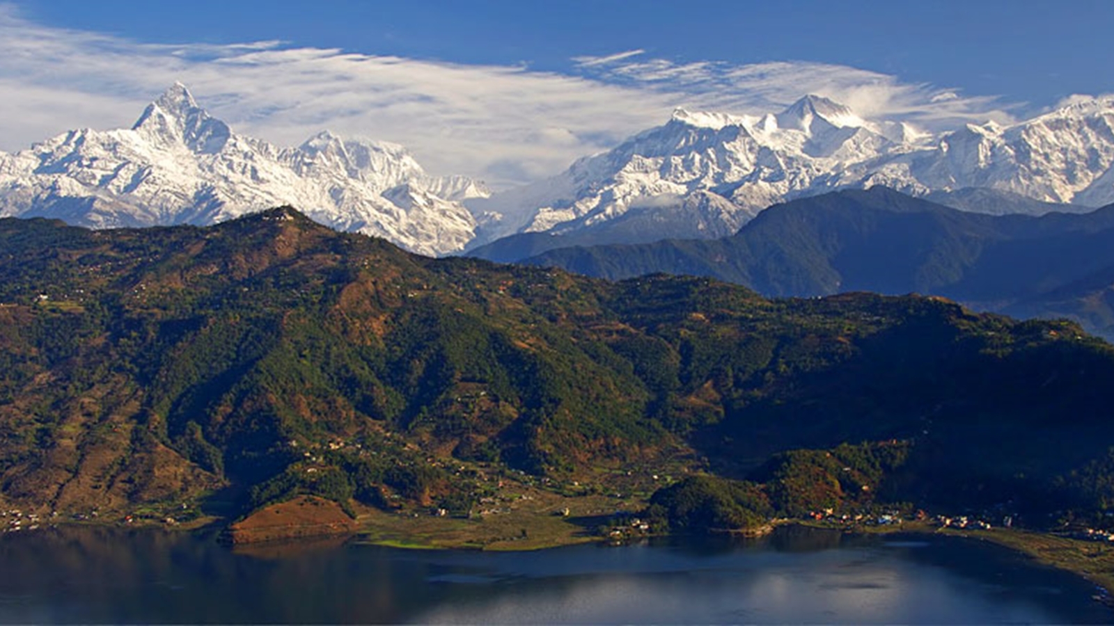 Scenic view of the snow-capped Annapurna mountain range with lush green hills and Phewa Lake in Pokhara, Nepal