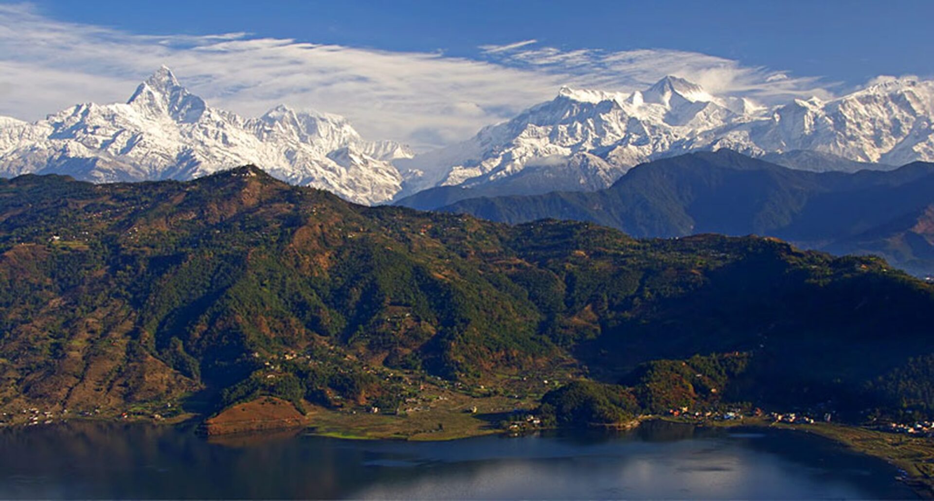 Scenic view of the snow-capped Annapurna mountain range with lush green hills and Phewa Lake in Pokhara, Nepal