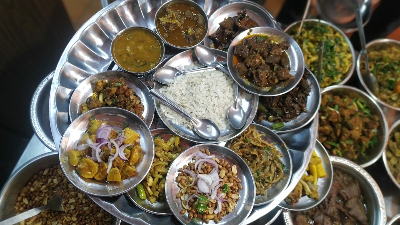 Traditional Nepali and Newari dishes served on a large metal platter with various curries, vegetables, rice, and condiments.