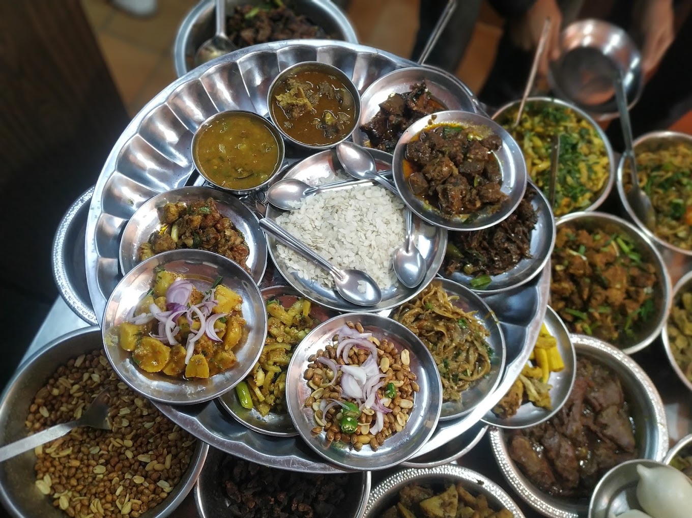 Traditional Nepali and Newari dishes served on a large metal platter with various curries, vegetables, rice, and condiments.